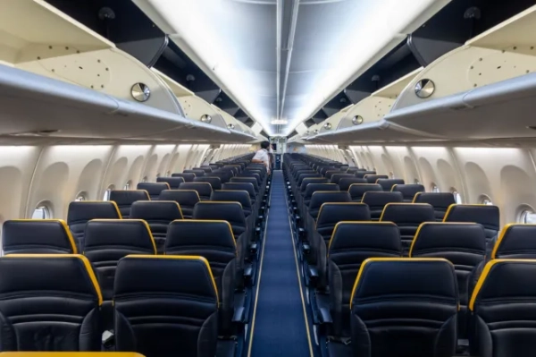 Порожній прохід літака Ryanair з сидіннями з обох боків та порожніми верхніми багажними полицями.