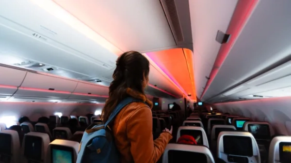 Жінка сідає в літак з невеликим рюкзаком на собі.