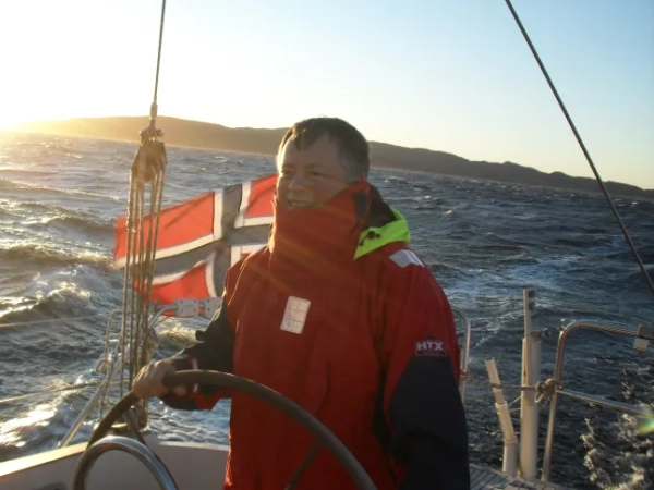 Рольф Твербакк, родом з Норвегії, на кораблі з норвезьким прапором та зимовим фоном позаду нього.