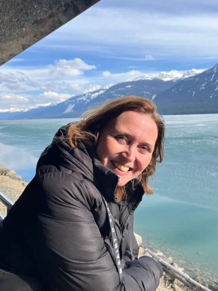 Наша письменниця Аманда Кейбл стоїть на борту човна з видом на воду, схилившись над поручнями та посміхаючись у камеру.