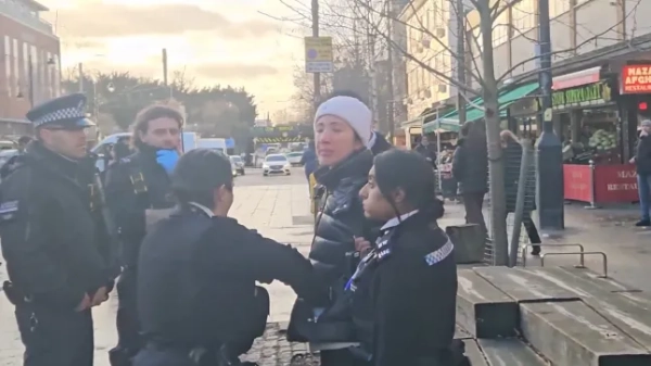 Жінка в кайданках стоїть на головній вулиці після арешту в оточенні поліцейських та членів міської ради