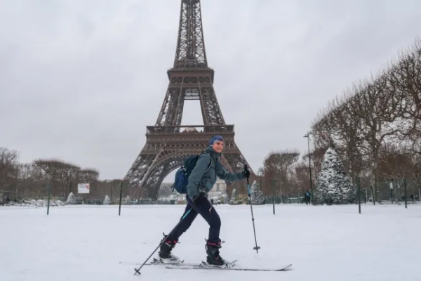 Лижник пролітає повз Ейфелеву вежу на Марсовому полі, вкриту снігом після снігопадів у Парижі, 7 січня 2026 року. Згідно з оголошеннями Ile-de-France Mobilit?s (IDFM) та RATP, усі автобуси в Парижі та навколишньому регіоні поступово припинили рух близько 7 ранку через поновлення снігопадів у цьому районі та повернулися до своїх депо. Сніг та лід вражають північну та західну Францію, явище «рідкісного масштабу в нинішньому кліматі», згідно з Meteo-France, яке, як очікується, спричинить значні обмеження на дорогах та повітряному транспорті. (Фото Людовіка Маріна / AFP via Getty Images)