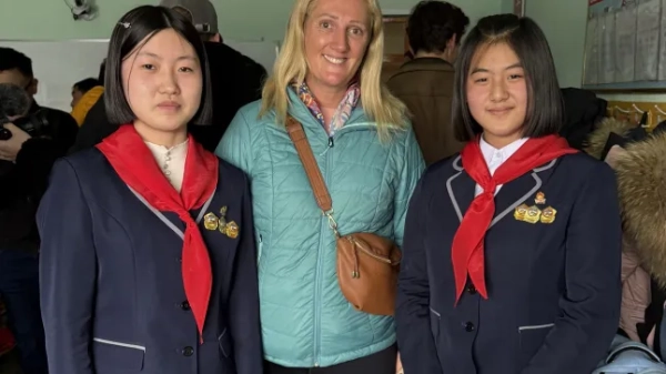 Джанет Ньюенхем у оточенні двох північнокорейських школярок у темно-синіх блейзерах та червоних шарфах у стилі скаутів