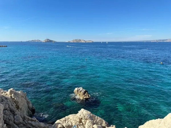 Вид на яскраве блакитне Середземне море з набережної Марселя. Вдалині видно невеликий човен і кілька крихітних островів.