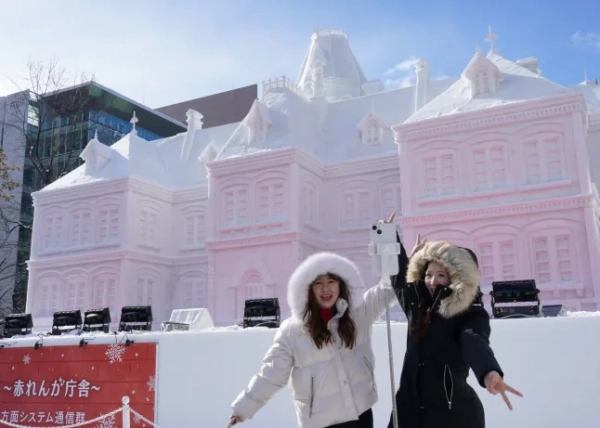 САППОРО, ЯПОНІЯ – 4 ЛЮТОГО: Жінки позують перед великою сніговою скульптурою «Колишня урядова установа Хоккайдо: будівля з червоної цегли», виставленою під час 75-го фестивалю снігу в Саппоро 4 лютого 2025 року в Саппоро, Японія. Фестиваль снігу в Саппоро, який проводиться щорічно на початку лютого, є однією з найвідоміших зимових подій Японії, що приваблює понад два мільйони відвідувачів, щоб помилуватися його приголомшливими сніговими та крижаними скульптурами на трьох основних майданчиках: парку Одорі, Сусукіно та Цудоме. Фестиваль, який розпочався в 1950 році з шести снігових скульптур, створених місцевими студентами, перетворився на світове видовище з масштабним сніговим мистецтвом, освітленими дисплеями та різноманітними зимовими розвагами. (Фото Крістофера Джуе/Getty Images)