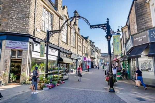 Затишна вулиця в Гаррогейті, Північний Йоркшир, з квітами, що продаються на тротуарі, та людьми, які роблять покупки.