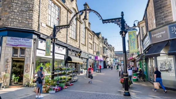 Затишна вулиця в Гаррогейті, Північний Йоркшир, з квітами, що продаються на тротуарі, та людьми, які роблять покупки.