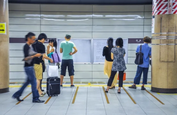Люди чекають на поїзд, стоячи на жовтій лінії на станції метро