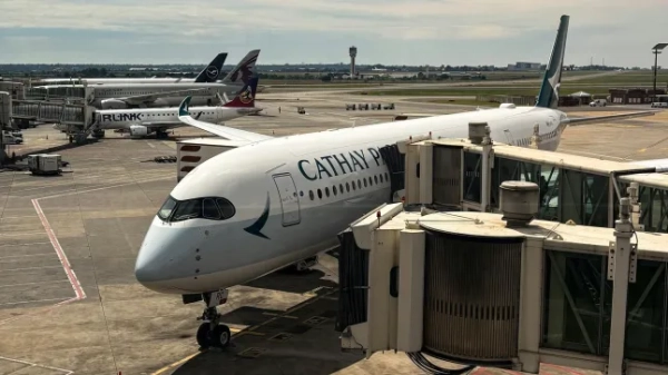 Літак Cathay Pacific стоїть на злітній смузі аеропорту.