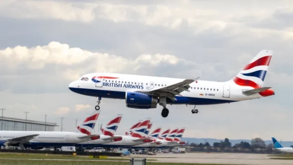 Літак British Airways приземляється в лондонському аеропорту Хітроу, а позаду нього на злітній смузі стоїть ряд літаків BA.