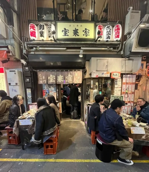 Вуличний бар зі столами та стільцями на вулиці, повний людей, на вулиці в Токіо, Японія