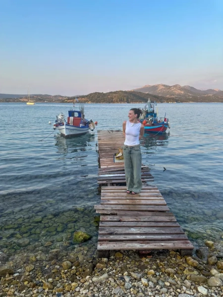 Еліс Мерфі в джинсах та білій майці на пірсі в морі на Лефкаді