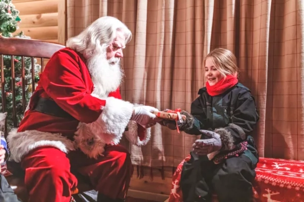 Санта Клаус вручає подарунок молодій блондинці в затишній кімнаті