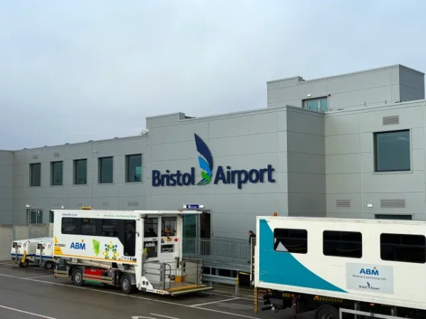 Мальовничий вид на перон з автобусом та написами на фасаді будівлі аеропорту в британському аеропорту Брістоль у похмурий зимовий день.