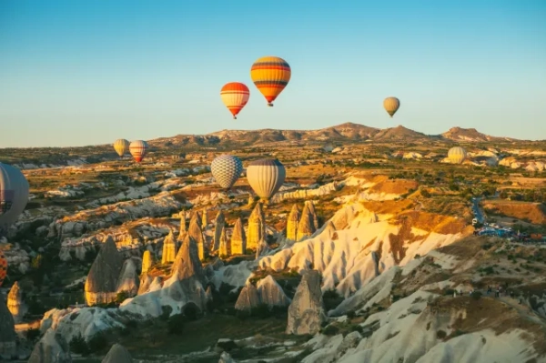 Повітряні кулі літають у небі на світанку над ландшафтом Каппадокії, Туреччина.