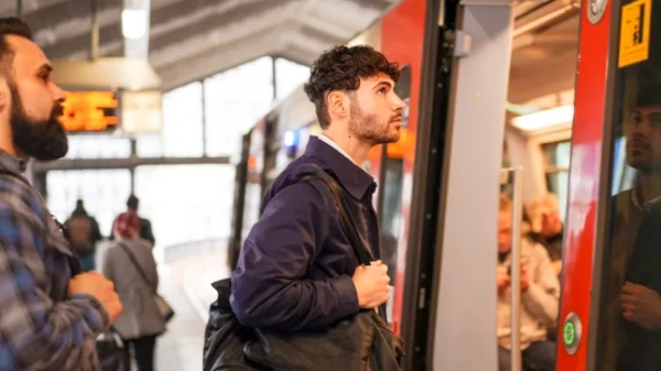 Вид збоку молодого підприємця, що сідає на поїзд на залізничній станції