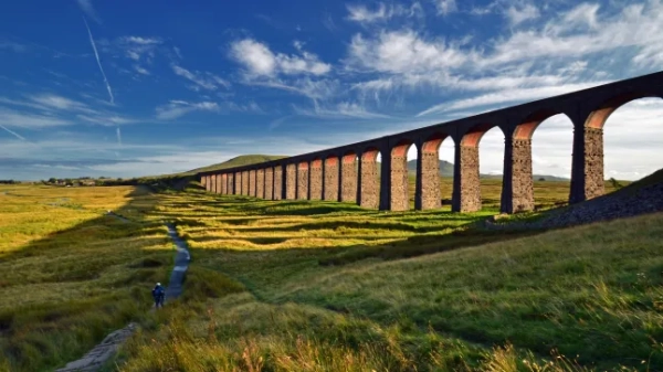 Приголомшливий вид на високий арочний міст Рібблхед Віадук, над полями та під сонячним блакитним небом.
