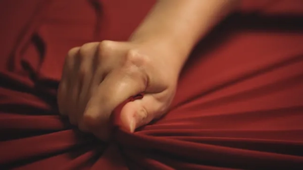 Жіноча рука пристрасно стискає червоне простирадло
