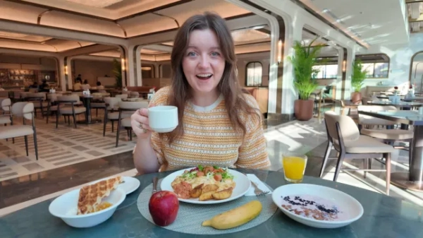 Я пройшов усю країну менш ніж за 5 годин 20 Челсі Дікенсон посміхається, снідаючи в готелі, а перед нею на столі стоять різноманітні тарілки, фрукти та напої.