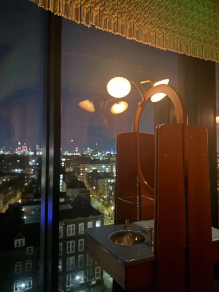 Вікна від підлоги до стелі у ванній кімнаті готелю Decimo з видом на нічний горизонт Лондона