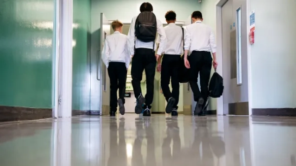 Рівень поверхні, вид підлітків, які йдуть по підлозі в шкільному коридорі, вид ззаду