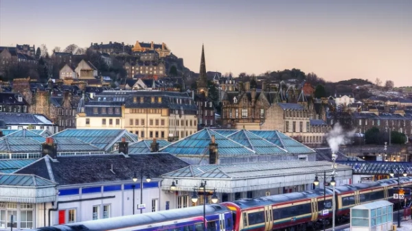 Найгарніші міста та села Великої Британії, які варто відвідати цієї зими 21 Місто Стерлінг у Шотландії на світанку, з будівлями, що визирають над залізничним вокзалом, на платформі якого стоїть поїзд.
