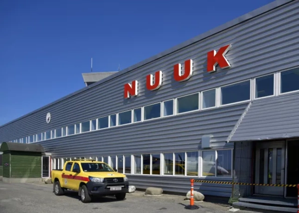 Нуук / Годтхаб, Гренландія: Аеропорт Нуук у сонячний літній день - металева облицьована сторона терміналу, видно з перону (IATA: GOH, ICAO: BGGH) - вивіска Nuuk великими червоними літерами та жовтий пікап оператора аеропорту, Адміністрації аеропорту Гренландії.
