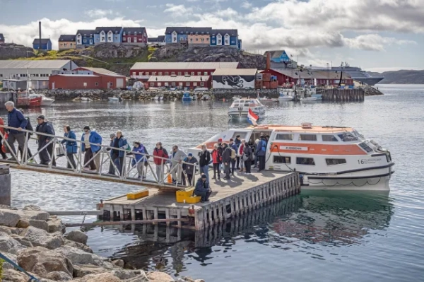 Какорток, Юліане??б, Гренландія, Данія - 17 серпня 2024 року: рятувальні човни великих кораблів доставляють туристів з круїзних лайнерів до невеликої гавані, оскільки гавань недостатньо велика, а кількість людей у місті за день збільшується більш ніж удвічі.