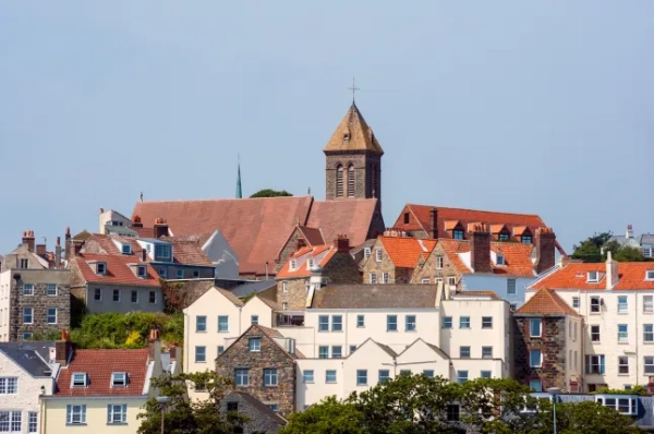 Горизонт гарних будинків та вежі в порту Сент-Пітер на острові Гернсі в яскравий день.