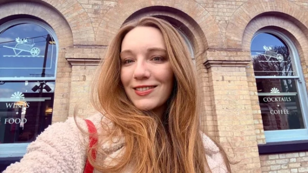 Кортні Почін посміхається біля пабу «Tap on the Line» в К'ю.