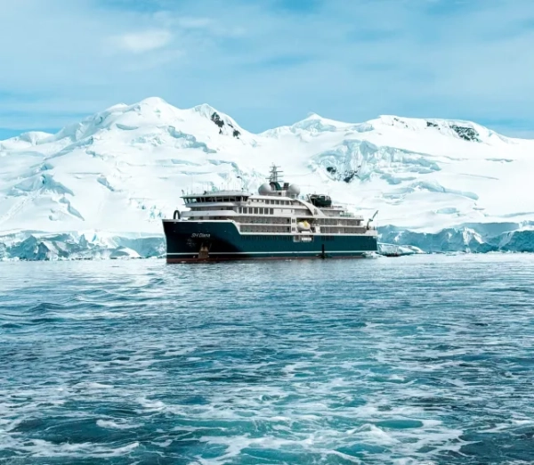 Круїзний лайнер на воді в Антарктиді з льодовиком позаду нього