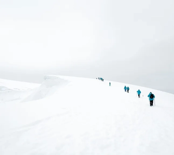 Група людей йде вдалині через засніжений льодовик в Антарктиді