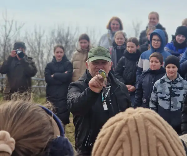 A birdringer holds a tiny migratory bird in the middle of a crowd of people in Palanga, Lithuania