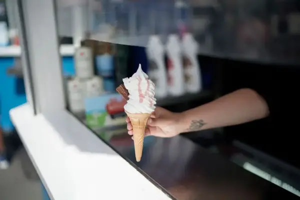 A vendor serves an ice cream from behind a perspex panel on Llandudno promenade after pandemic travel restrictions were eased on July 06, 2020 in Llandudno, United Kingdom. (Photo by Christopher Furlong/Getty Images)