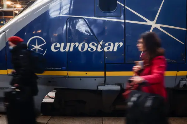 A woman walking in front of a blue Eurostar train in Gare du Nord