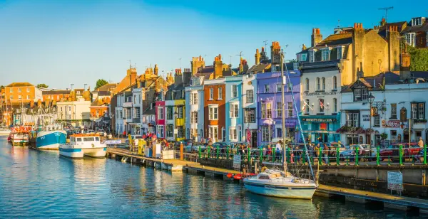 Colourful terraced houses, fishing boats and yachts around the harbour in Weymouth, Dorset.