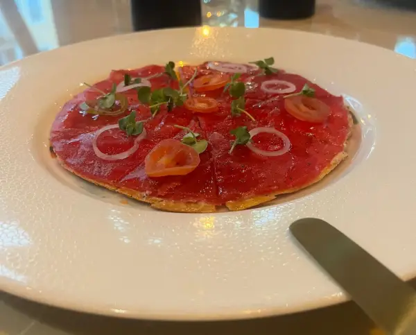 A plate of tuna crudo in the shape of a pizza