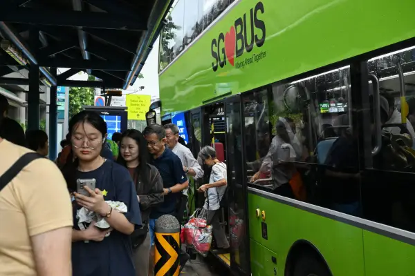 People alight from a public bus in Singapore on September 21, 2026. Riders who eat on public buses or put their feet on the seats now face a nearly 500 SGD (392 USD) penalty in Singapore, officials said September 21, a new example of no-nonsense rules in 