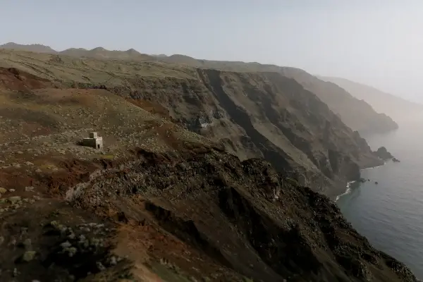 a small isolated house on a steep volcanic cliff