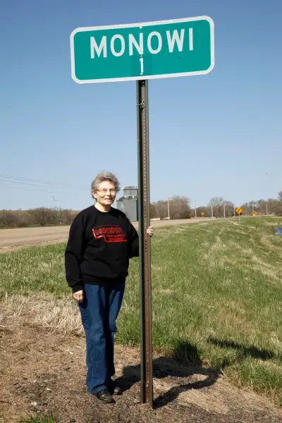 Monowi: американське село, де живе одна людина 12 Elsie Eiler posing with the town population sign outside of the village of Monowi, Nebraska, with the abandoned town grain elevator in the background.
