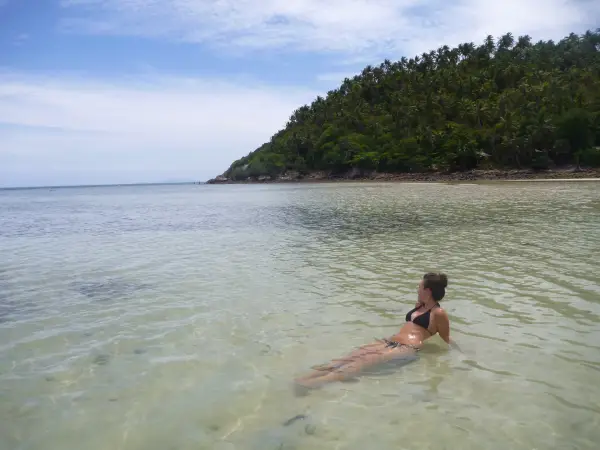Writer Lydia Swinscoe lies in the water on a beach.