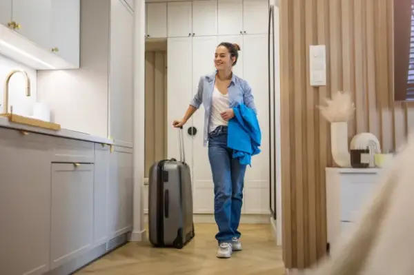 Young woman entering rented apartment with luggage?; Shutterstock ID 2450731025; purchase_order: -; job: -; client: -; other: