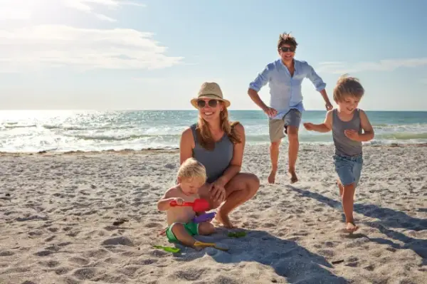 Happy, parents and children playing on the beach on family travel, holiday or adventure in summer. Boy, father and kids with outdoor ocean for fun energy and happiness with a game while running; Shutterstock ID 2472674489; purchase_order: -; job: -; client: -; other: -
