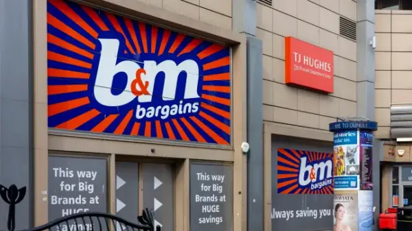 Exterior of a B&amp;M Bargains logo outside the Wellgate Shopping Centre in Dundee , on March 22, 2025. Prominent, advertising "Big Brands at HUGE savings." A directional sign further indicates the store's location in the retail mall.